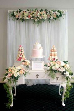 the wedding cake is sitting on top of the white table with flowers and greenery