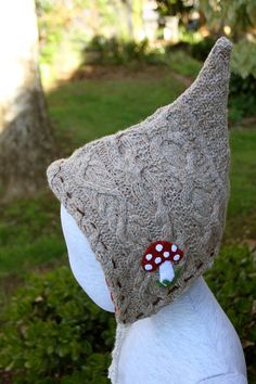 a close up of a person wearing a knitted hat with a mushroom on it