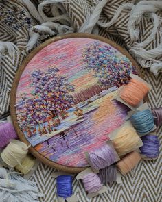 an embroidery project with yarn and thread on a tablecloth next to a basket full of skeins