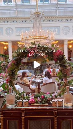 the interior of a hotel with flowers and greenery on display in front of an ornate chandelier