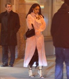 a woman is walking down the street in a pink coat