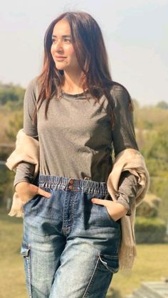 a woman standing in front of a fence with her hands on her hips