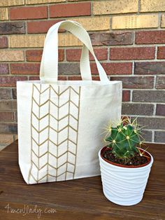 a white tote bag sitting next to a potted cactus on top of a wooden table