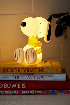 a lamp that looks like a dog sitting on top of some books with the light turned on