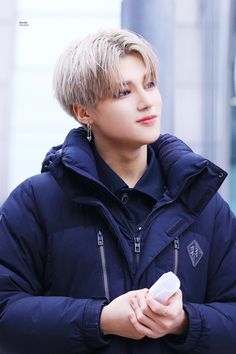 a young man in a blue jacket holding a white object