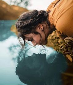 a woman leaning over the edge of a body of water