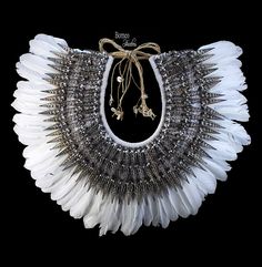 A large New Guinea white braided rope curved necklace with a fan of long Feather drops, and a collar of three overlapping rows of long pointed black sliced Shells. The biggest sliced Shells are 2.75 inches in length and the smallest are 2 inches in length. The inner diameter of the collar is, approximately 5 inches, and the maximum outer width of the necklace is, approximately 22.75 inches. The necklace has a maximum drop length of 18 inches, and is attached, at the top, by two groups of cream c Adjustable White Feather Jewelry, White Bohemian Ceremonial Necklace, Feather Diy, Feather Decor, Traditional Earrings, Braided Rope, New Guinea, Wedding Necklace, Sea Shells