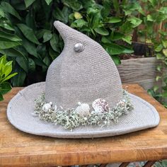 Perfect for a witch who feels a deep connection to the sea, this beige hat features dried moss and lichen, crystals, shells and faux pearls.  This hat will keep you shaded on warm days, and warm on cool evenings. Please note that colors may differ slightly due to differences in screen calibration. This lower profile hat is about 10" high making it great for dress up or everyday wear, and is sure to turn heads.  The brim diameter is about 14" and just enough to provide some shade on those warmer days.   The hat has a sloped shape that allows it to fit most folks comfortably. Materials: wool blend Care: Spot clean as needed with damp cloth Please note that this item ships folded flat.  It will regain its shape with wear. Sea Witch Fashion, Sea Witch Clothes, Sea Witch Hat, Green Witch Hat, Sea Witch Cosplay, Beige Hat, Sea Witch, Costume Hats, Witch Hat