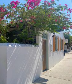 a white house with pink flowers on the tree