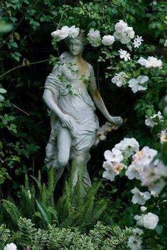 a statue is surrounded by flowers and greenery