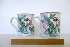 two coffee mugs with hummingbirds painted on them