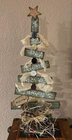 a small christmas tree made out of wood with buttons and ribbons on it's sides