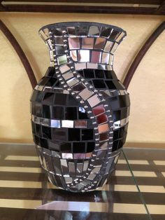 a mosaic vase sitting on top of a glass table