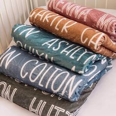 four blankets stacked on top of each other in different colors and designs, all with the names of their respective cities