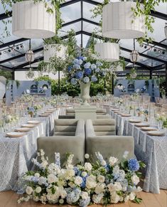 an outdoor dining area with tables, chairs and vases filled with blue and white flowers