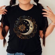 Whimsical Moon and Star Celestial Print Black T-Shirt Introducing our stunning celestial-themed t-shirt, featuring a whimsical moon and sun print against a sleek black background. This one-of-a-kind piece is perfect for anyone who loves celestial designs and wants to add a touch of magic to their wardrobe. Made from high-quality materials, our t-shirt is soft, comfortable, and durable, making it ideal for everyday wear. The short-sleeved design ensures you stay cool and comfortable, while the flattering fit and black color make it easy to style with any outfit. The eye-catching celestial print features a detailed moon and sun design, with intricate patterns and vibrant colors that really pop against the black background. Whether you're looking for a statement piece for a night out or a uni Sun And Moon Graphic, Sun And Moon Shirt, Whimsical Moon, Bohemian Sun, Celestial Shirt, Star Celestial, Moon Lover, Celestial Print, Moon Graphic