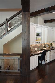 an open kitchen with white cabinets and wood flooring, along with a staircase leading up to the upper level