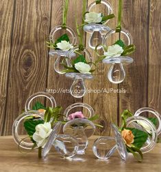 several clear vases with flowers in them sitting on a table next to a wooden wall