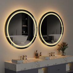 two round mirrors are above the sinks in this modern bathroom with marble countertops and gray cabinets