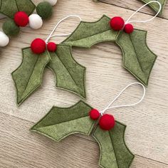 two felt holly wreaths with red and white pom - poms on them