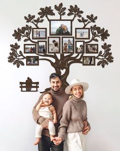 a man and woman standing next to a tree with family photos on it