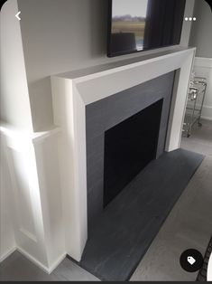 a flat screen tv mounted on the wall above a fireplace in a room with white walls