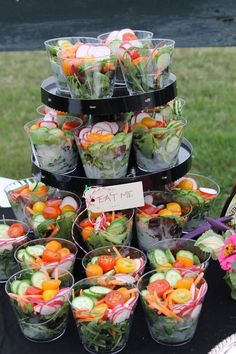 a table topped with lots of salads and cups filled with different types of vegetables