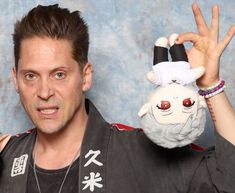 a man holding up a stuffed animal in front of his face with one hand and two fingers