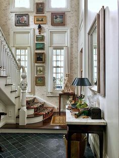 a staircase with pictures on the wall and a lamp in front of it next to a table