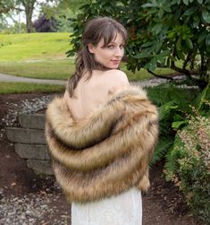 a woman in a white dress is wearing a fur shawl and posing for the camera