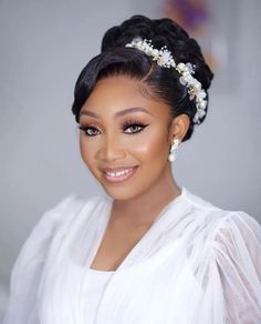 a woman wearing a white dress and pearls in her hair, smiling at the camera