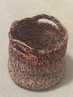 a woven basket sitting on top of a white counter next to a brown and pink object