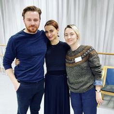 a man and two women standing next to each other in front of a white curtain