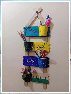 a wall hanging made out of popsicle sticks and plastic cups with writing on them