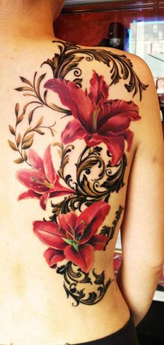 the back of a woman's tattoo with red flowers on her upper arm and shoulder