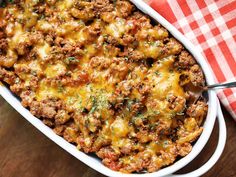 a casserole dish filled with meat and cheese on top of a checkered table cloth