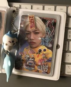 a keychain with an image of a person and a cat on it next to a keyboard