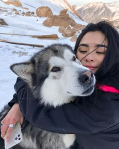 a woman hugging a husky dog in the snow