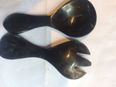 two black spoons sitting next to each other on top of a white tablecloth