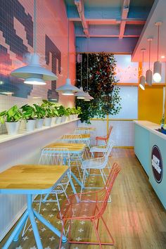 an empty restaurant with colorful chairs and plants