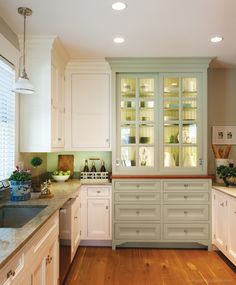 a kitchen with white cabinets and wood floors