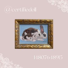 a painting of a rabbit in a gold frame on a pink background with the words certified doll above it