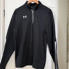 a black jacket hanging on a door with a hanger in front of it that says under armour