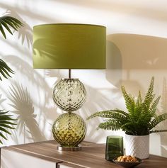 a table with two vases and a lamp next to it on top of a dresser