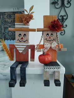 two wooden dolls sitting on top of a counter next to an apple and cornucopi