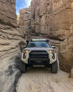 the front end of a silver four - doored truck parked on a rocky terrain