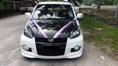 a black and white car with purple ribbon tied to the hood