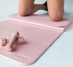 a woman laying on top of a pink mat with two dumbs attached to it