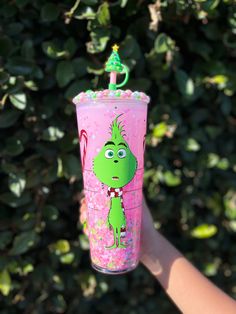 a person holding up a pink cup with the grin face on it and a green top