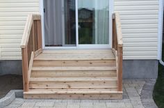 wooden steps leading up to the front door of a house with sliding glass doors on both sides